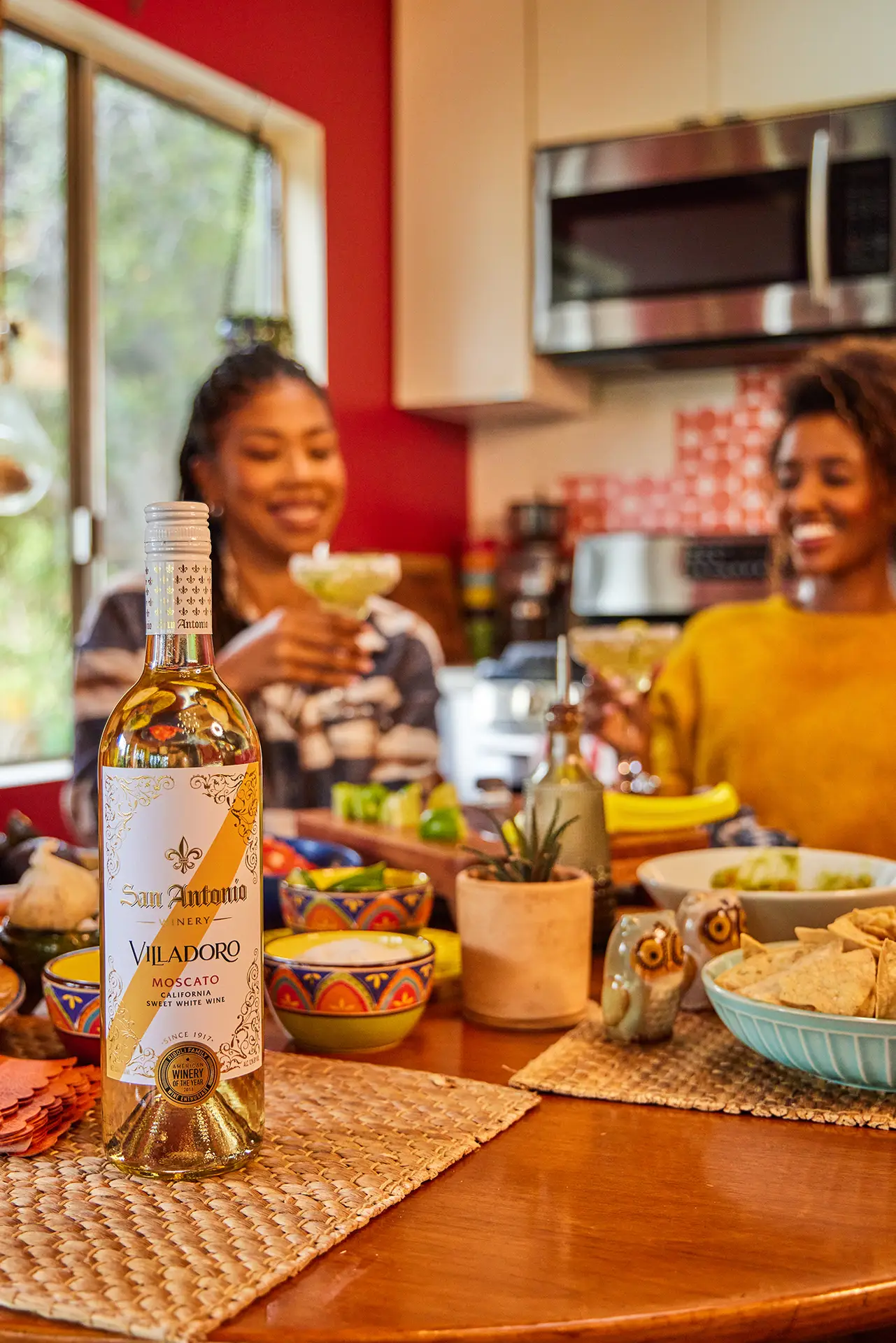Friends laughing and holding San Antonio Winery Imperial wine at a backyard barbecue.
